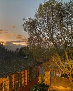 a house with a tree in front of a sunset at Hacienda Hato Verde in Mulaló