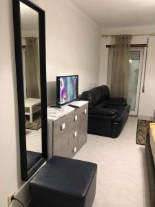 sala de estar con espejo y sofá de cuero negro en VC Alojamentos, en Seia