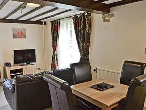 sala de estar con mesa y sillas de cuero en Cartmel Cottage, en Lindale