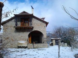 a small stone building with a balcony in the snow at Stone Mountainhouse near Kalavryta, North Peloponnese, Greece 