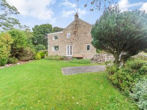 an old stone house with a grass yard at Cherry Tree Cottage in Burtree Ford