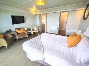 a bedroom with a large bed and a table and chairs at Whispering Sands Beachfront Motel in Gisborne