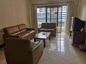 a living room with couches and a tv and a table at Homestay Marina Court Kota Kinabalu Sabah in Kota Kinabalu