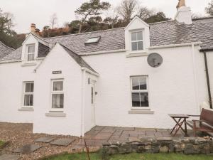 ein weißes Haus mit einem Picknicktisch davor in der Unterkunft Craigard in Balmacara