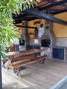 a wooden bench in a room with a brick wall at Refúgio Peró - Praia, piscina e churrasqueira in Cabo Frio