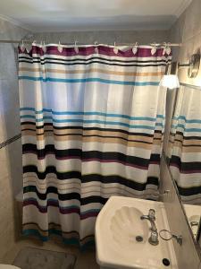 baño con lavabo y cortina de ducha en Dúplex la Caleta en Mar de Cobo