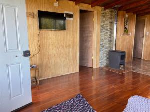 Cabaña estero Huite في Quemchi: غرفة معيشة مع أرضيات خشبية وتلفزيون بشاشة مسطحة