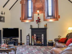 a living room with a fireplace and a tv at Ardlui Church in Ardlui