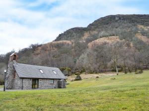 a stone house in a field in front of a mountain at Ardlui Church in Ardlui