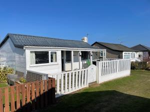ein kleines weißes Haus mit einem weißen Zaun in der Unterkunft Seabirds - 3 bed chalet, dog friendly, Bridlington in Bridlington
