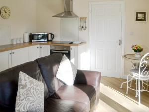 sala de estar con sofá de cuero en la cocina en High Trees Annex, en Widdrington