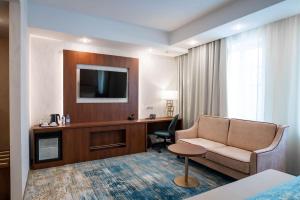 a hotel room with a couch and a desk at Best Western Plus Oskemen in Ustʼ-Kamenogorsk