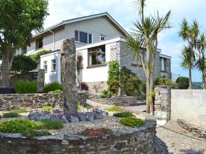 uma casa com uma palmeira e uma parede de pedra em Sowenna - Ukc3537 em Mevagissey