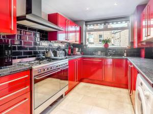 una cucina rossa con armadi rossi e lavandino di Tapestry House a Bridlington