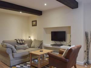 a living room with a couch and a tv at Rosemount Cottage in Salterforth