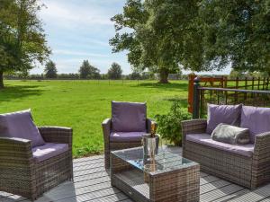 a patio with two chairs and a table and a field at Park View - Ukc4925 in Roydon