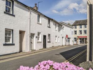 una calle vacía con casas blancas y flores rosas en Pollywiggle Cottage, en Keswick
