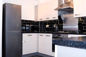 a kitchen with white cabinets and a stainless steel refrigerator at Modern 3 Bed House in Wolverhampton