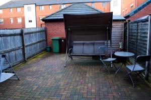 een patio met 2 stoelen, een tafel en een hek bij Modern 3 Bed House in Wolverhampton