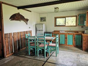 Una cocina con mesa y sillas y un refrigerador. en Cabaña Canto del Zorzal, en Villarrica