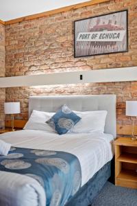 1 dormitorio con cama y pared de ladrillo en The Settlement Historic Hotel, en Echuca