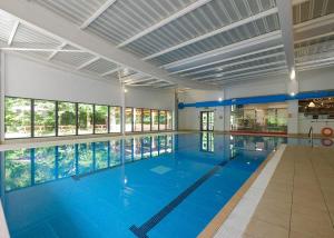 a large swimming pool with blue water in a building at Fell End in Milnthorpe