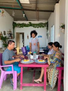 een groep mensen die rond een roze tafel zitten bij Puro Paraíso Eco Hotel in Taganga