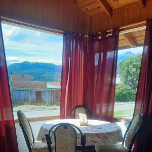 mesa y sillas en una habitación con ventana grande en Cabaña acogedora en el centro de Epuyen en Epuyén