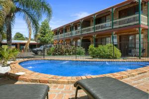 a swimming pool in front of a building at The Settlement Historic Hotel in Echuca