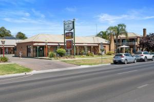a street with cars parked in front of a building at The Settlement Historic Hotel in Echuca