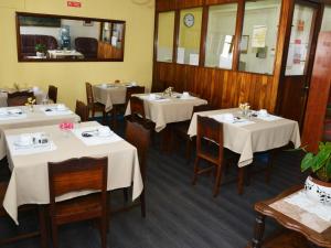 um restaurante com mesas e cadeiras com toalhas de mesa brancas em Pensao Astoria no Funchal