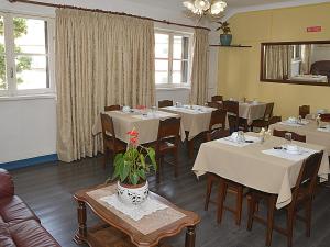 uma sala de jantar com mesas, cadeiras e janelas em Pensao Astoria no Funchal