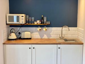 a kitchen counter with a sink and a microwave at The Snug at Caphays: perfect rural retreat in Long Burton