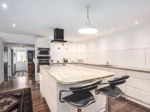 a kitchen with white cabinets and a counter with stools at Fieldview - Uk40947 in Auchtermuchty