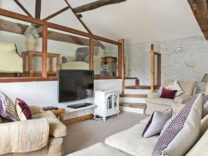a living room with couches and a flat screen tv at Lavender Cottage - Uk4061 in Buxton