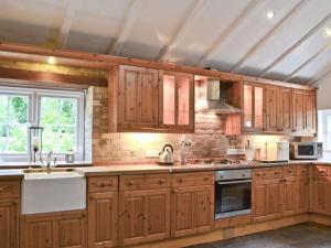 - une cuisine avec des placards en bois et un évier dans l'établissement Pigeon Coo Farmhouse, à Shalfleet
