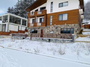 a house in the snow with benches in front of it at House Near Forest in Bakuriani