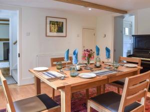 a dining room with a wooden table and a piano at Greenbank in Veryan
