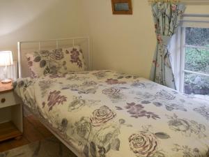 a bed with a floral bedspread and a window at Blackberry Cottage in Kenton