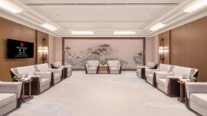 HUALUXE Hotels and Resorts Qingdao Licang, an IHG Hotel في تشينغداو: قاعة اجتماعات بها كراسي وجدار به لوحة