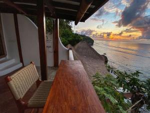 einen Holztisch und Stühle auf einem Balkon mit Blick auf das Wasser in der Unterkunft The Hidden Escapes- Unique Tiny Home on Bingin Beach with Breathtaking Ocean & Sunset Views in Uluwatu