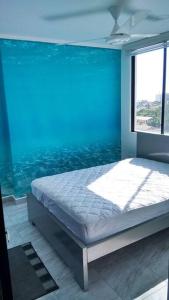 uma cama num quarto com uma grande janela em Departamento Familiar y bien cuidado. Wifi, piscina y jacuzzi em Tonsupa