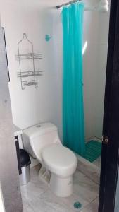 a bathroom with a toilet and a blue shower curtain at Departamento Familiar y bien cuidado. Wifi, piscina y jacuzzi in Tonsupa