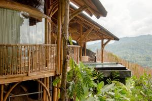 a wooden house with a balcony and mountains in the background at Dreamy Cliffside Bamboo Villa with Pool and View in Klungkung
