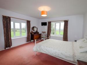 um quarto com uma cama, uma secretária e janelas em The Manor House at Kenwick Lodge em Ellesmere