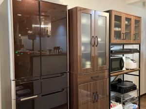 a kitchen with a stainless steel refrigerator and wooden cabinets at Nara Guesthouse 3F in Nara