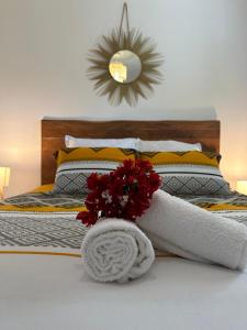 Una cama con una toalla blanca y flores rojas. en Sunset Appart, T2 avec vue mer et plage à 1 km, en Le Carbet