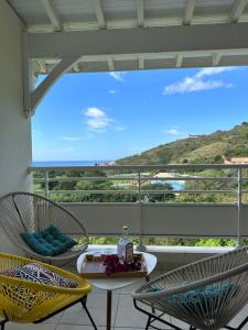 d'une terrasse avec 2 chaises et une table sur un balcon. dans l'établissement Sunset Appart, T2 avec vue mer et plage à 1 km, à Le Carbet