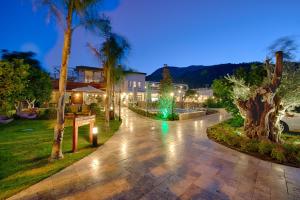 a walkway with palm trees and lights at night at Kimera Lounge Boutique Hotel & Spa in Cıralı