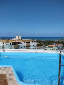 a large blue swimming pool with a view of the ocean at Flat JOÃO PESSOA JACUMÃ in Jacumã